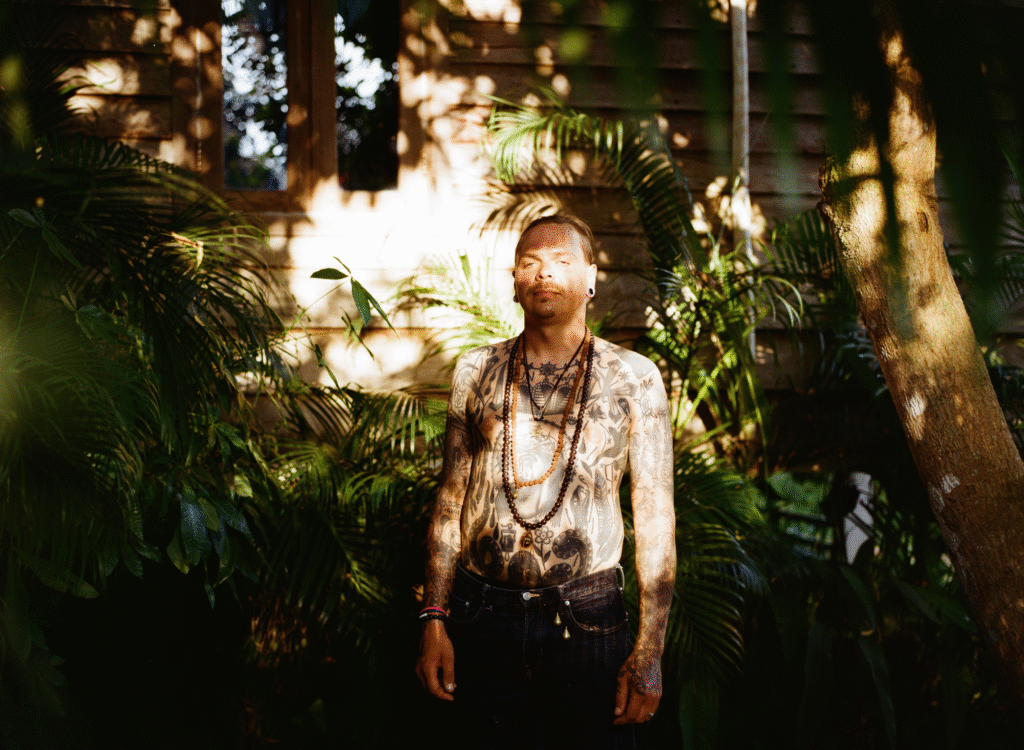 Portrait of heavily tattooed man standing in tropical garden, Japanese traditional tattoo artist Vilius Shanka in Vilnius